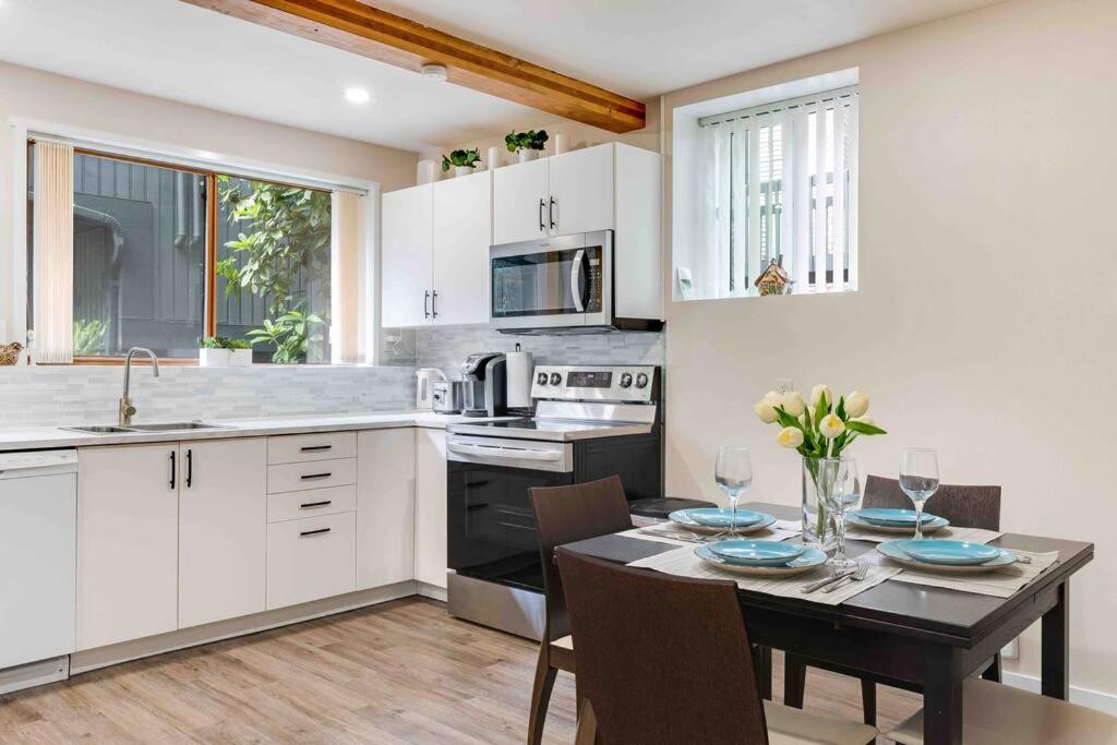 a kitchen with a dining table and a kitchen with white cabinets at Adorable new studio with free parking and WiFi in Federal Way