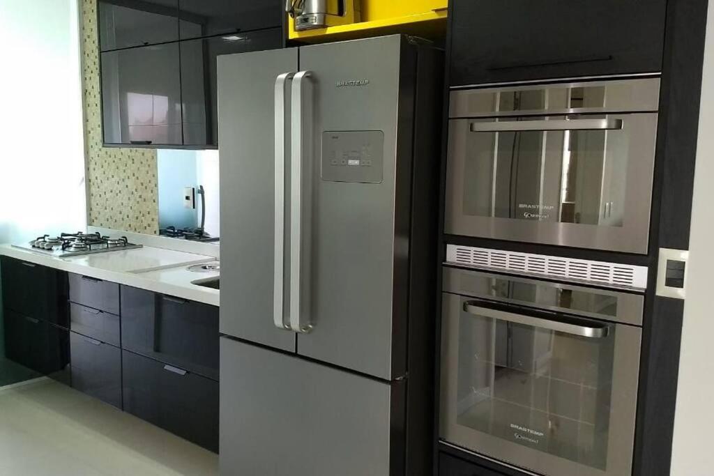 uma cozinha com um frigorífico de aço inoxidável e armários em Apartamento Duplex (Cobertura) Praia do Forte em Cabo Frio