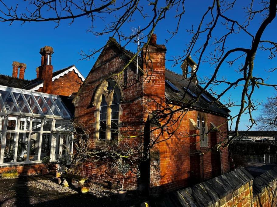 Un viejo edificio de ladrillo con una chimenea. en The Old School House Retreat, en Tibberton