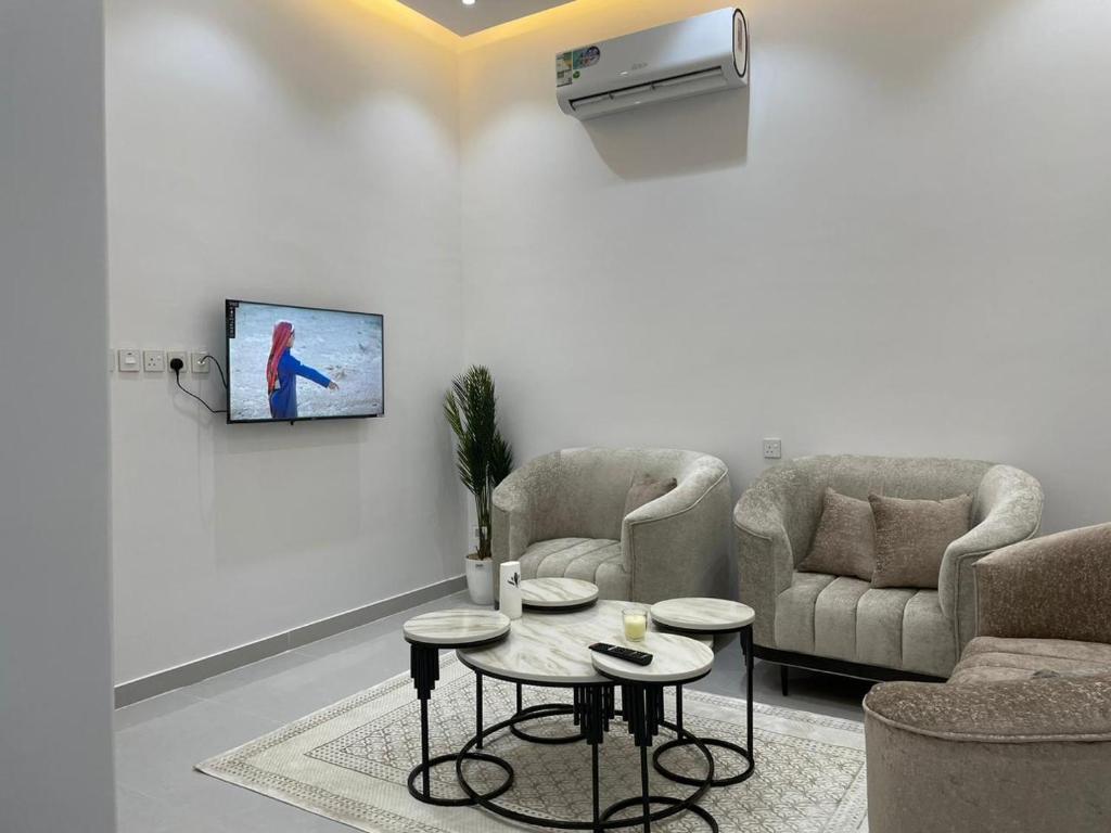 een woonkamer met 2 stoelen en een tv aan de muur bij شقة بغرفة وصالة in Hafr Al Baten