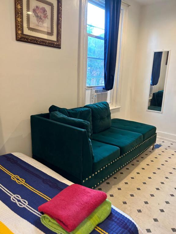a living room with a green couch and a window at Private room in Philadelphia
