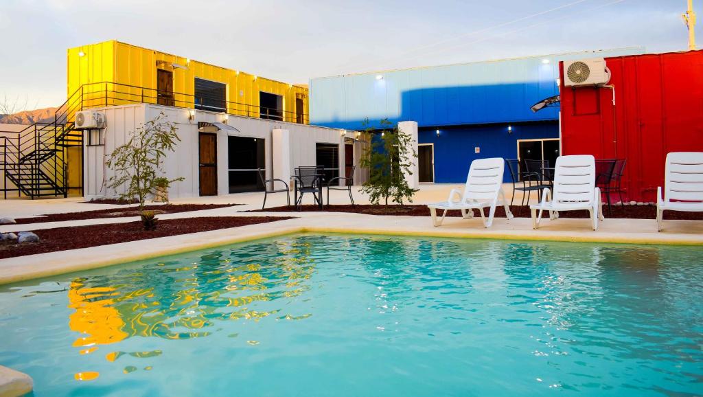 Vagón Resort في Cuatrociénegas de Carranza: مسبح امام مبنى فيه كراسي وطاولة