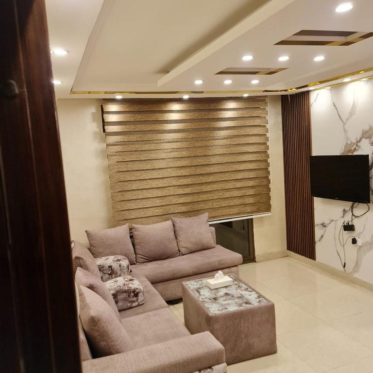 a living room with a couch and a flat screen tv at Quadro apartment in Amman