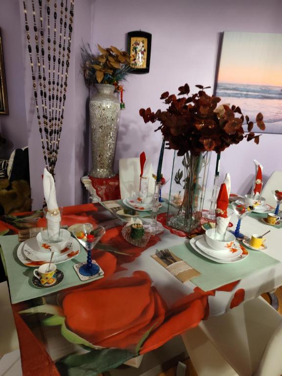 a dining room table with a table set with dishes and flowers at Fay guess house in Spanish Town
