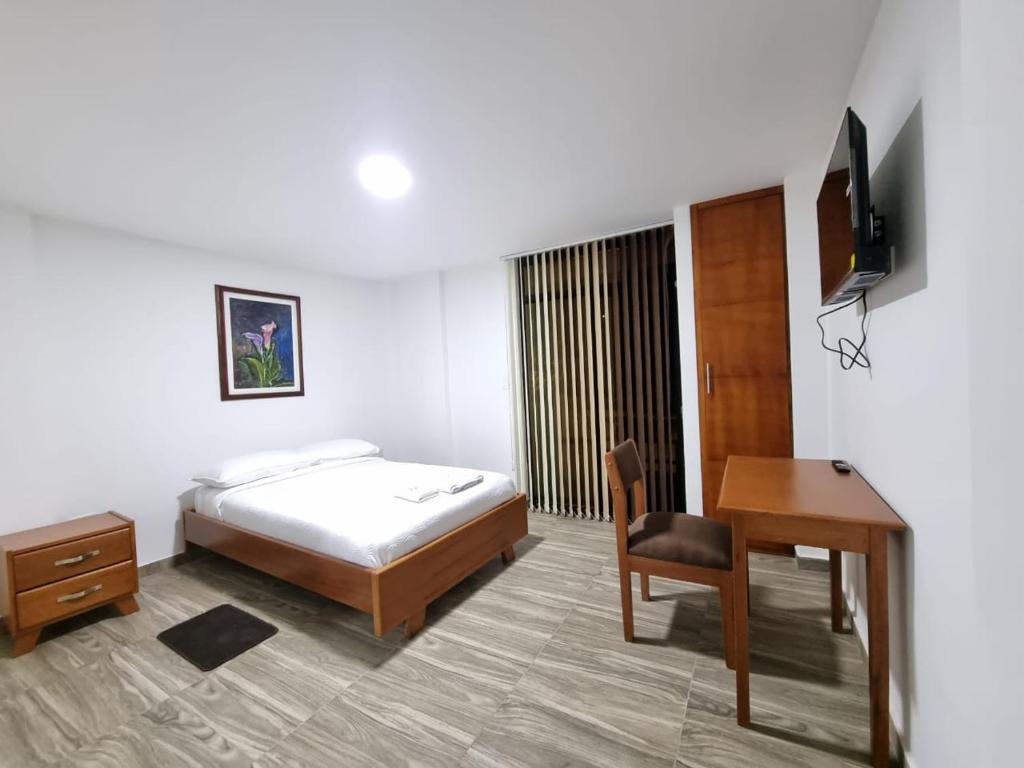 Schlafzimmer mit einem Bett, einem Schreibtisch und einem Tisch in der Unterkunft Hotel San Marcos Las Lajas in Ipiales