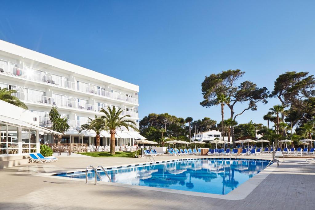 un hotel con piscina frente a un edificio en Globales Cala Blanca en Cala Blanca