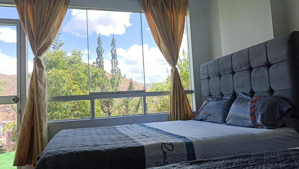 een slaapkamer met een bed en een groot raam bij Qori Garden Apartment in Cuzco