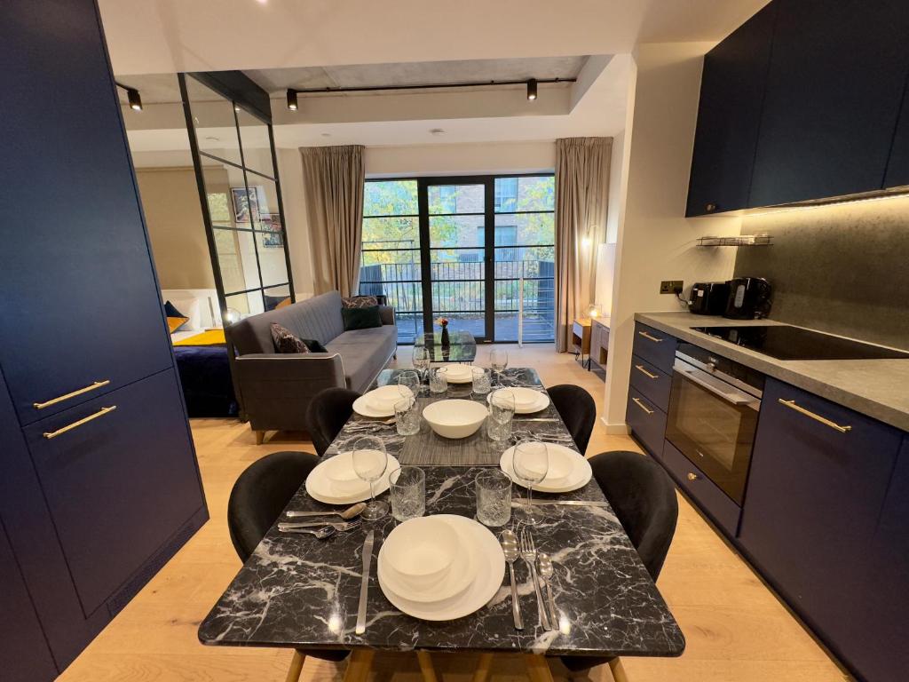 a kitchen and living room with a table with plates on it at London Luxury flat with Balcony, O2 Arena, Excel, Canary Wharf, Station in London