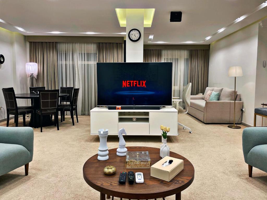 Una sala de estar con un televisor, un sofá y una mesa. en The Arabella House - Madinaty, en Madinaty