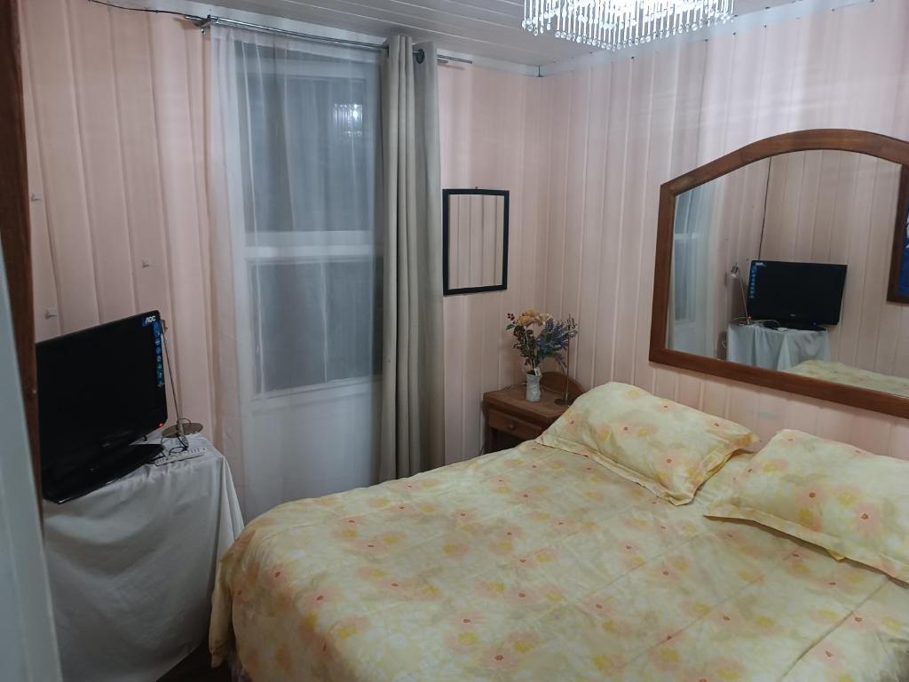 a bedroom with a bed and a mirror and a television at Marynes in Pucón