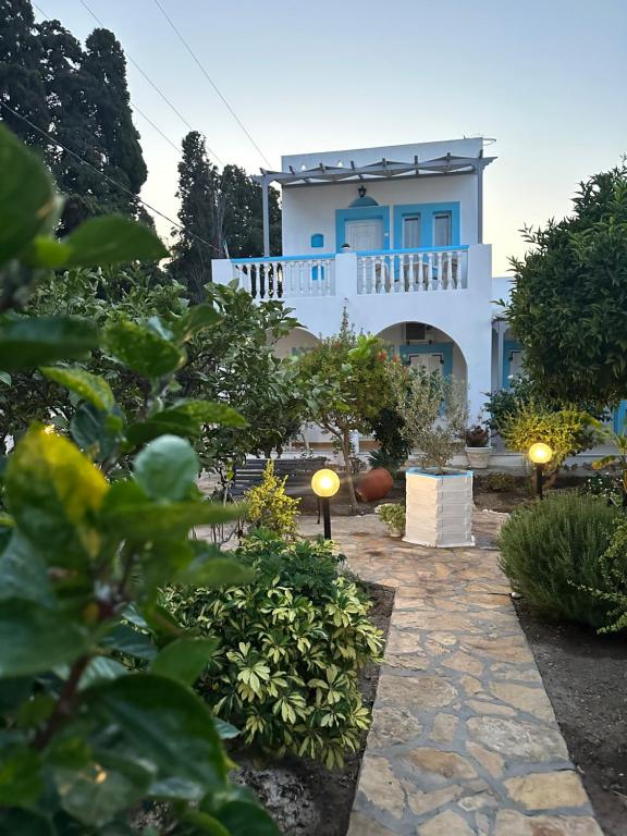 een wit huis met een blauw raam en een tuin bij EFFIE'S STUDIOS in Alinda