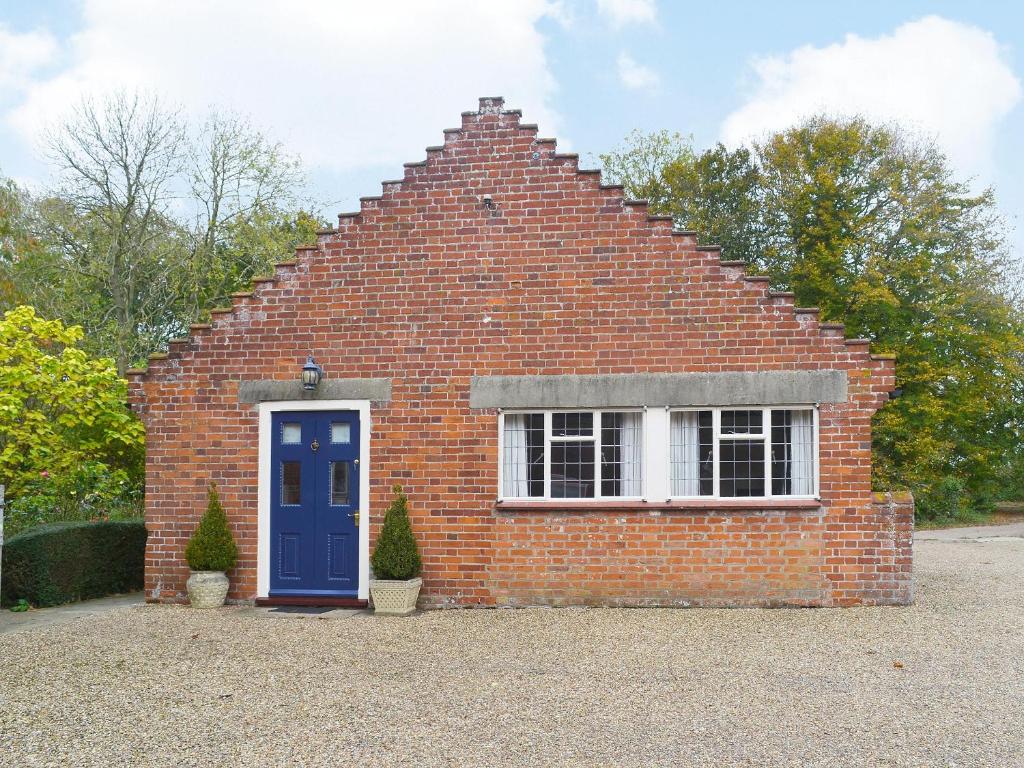 a brick house with a blue door and a window at The Cottage in Fressingfield