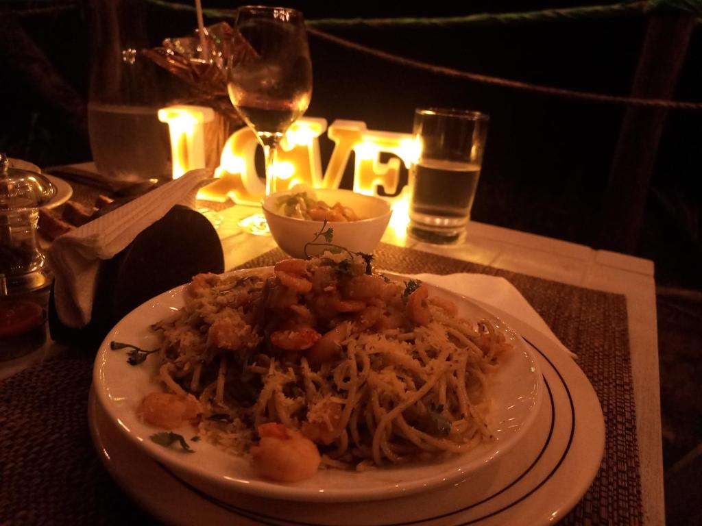 a plate of pasta on a table with a glass of wine at Cabañas Mangle House in Buenaventura