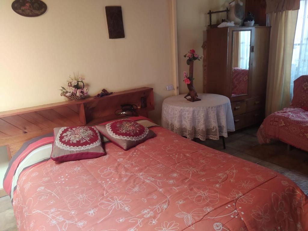 Un dormitorio con una cama roja con almohadas. en Casa habitacion condominio la Perla, en Isla Negra