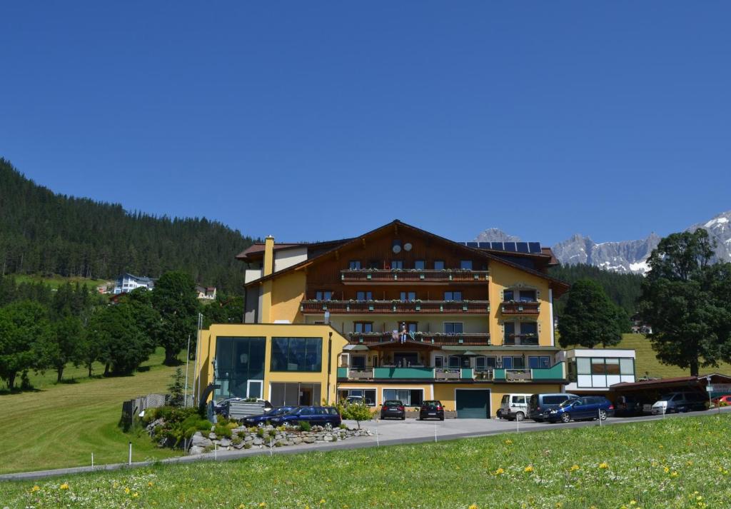 ein großes Gebäude mit davor geparkt in der Unterkunft Premium Wanderhotel Steirerhof in Schladming