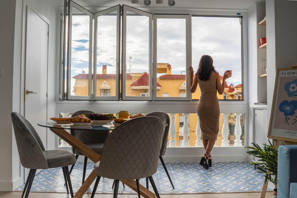 uma mulher olhando para fora de uma janela em uma mesa em Penthouse , Sea View @ Roof Top , 4 Min to Beach em Santa Pola
