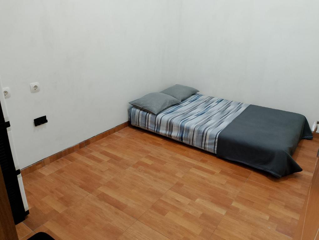 a bed in a white room with a wooden floor at Ador 46 Homestay Syariah & Kost in Mergan