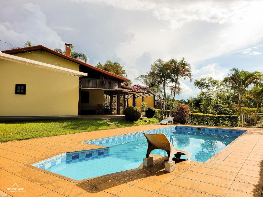 una piscina con una silla frente a una casa en Nosso Apê Enseada: Casa na Represa João Penido com Wifi, Piscina e Churrasqueira, en Juiz de Fora
