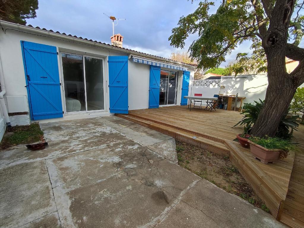 une maison avec des portes bleues et une terrasse en bois dans l'établissement Villa rénovée avec clim et terrasse à 150m de la plage - FR-1-776-3, à Argelès-sur-Mer