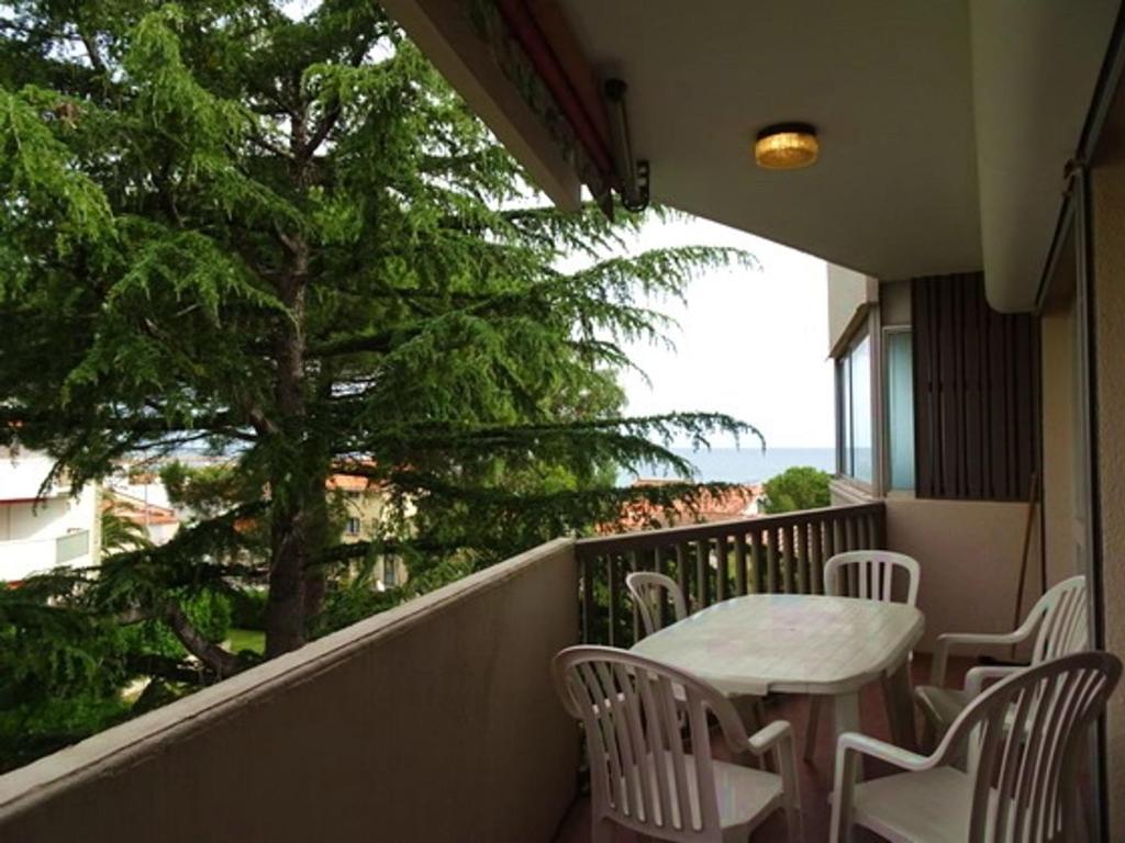 d'un balcon avec une table, des chaises et un arbre. dans l'établissement T2 à 50m de la plage avec piscine, parking et animaux acceptés - FR-1-776-19, à Argelès-sur-Mer
