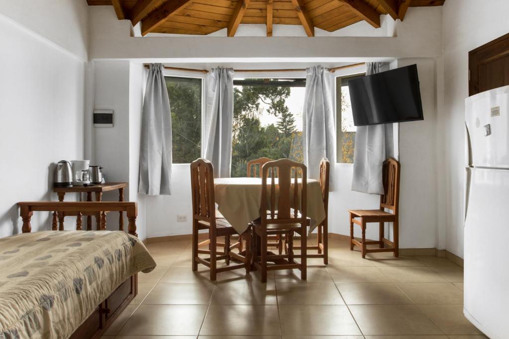 - une chambre avec une table, des chaises et une fenêtre dans l'établissement Rivendell Bungalows Bariloche, à San Carlos de Bariloche