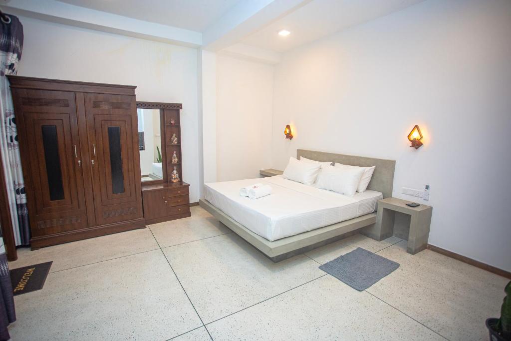 a bedroom with a white bed and a wooden cabinet at D2 Villa Unawatuna in Galle