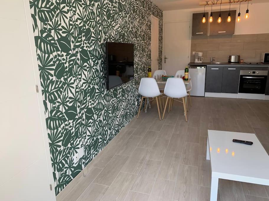 uma cozinha com cadeiras brancas e uma parede verde e branca em bellucciu di porto vecchio***. (Piscine chauffée) em Porto-Vecchio