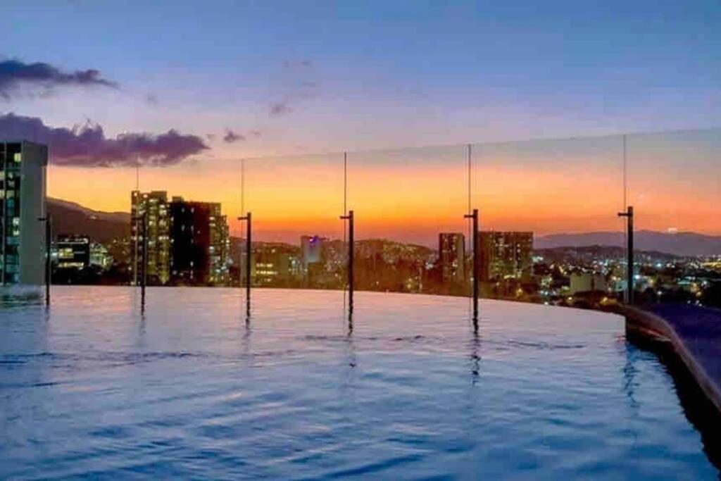 a swimming pool on top of a building with a city skyline at Pura Vida Hub - Iconnia in San José