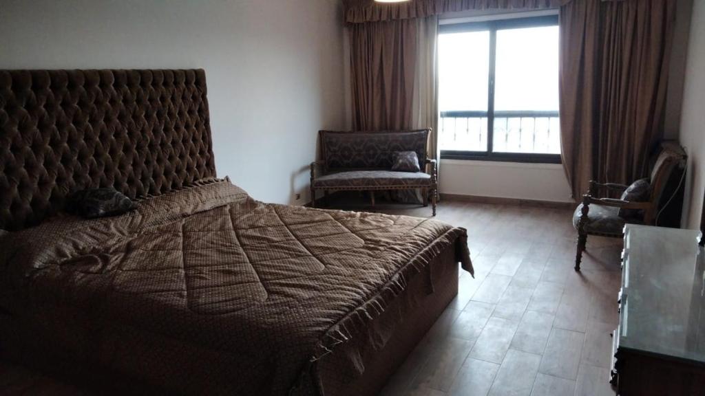 a bedroom with a bed and a chair and a window at شقة الزمالك علي النيل حي السفارات in Cairo