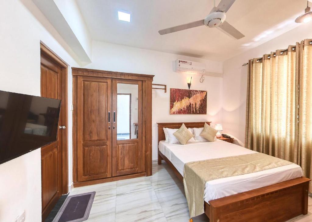 a bedroom with a bed and a flat screen tv at Kerawalapitiya Resort in Mahabage