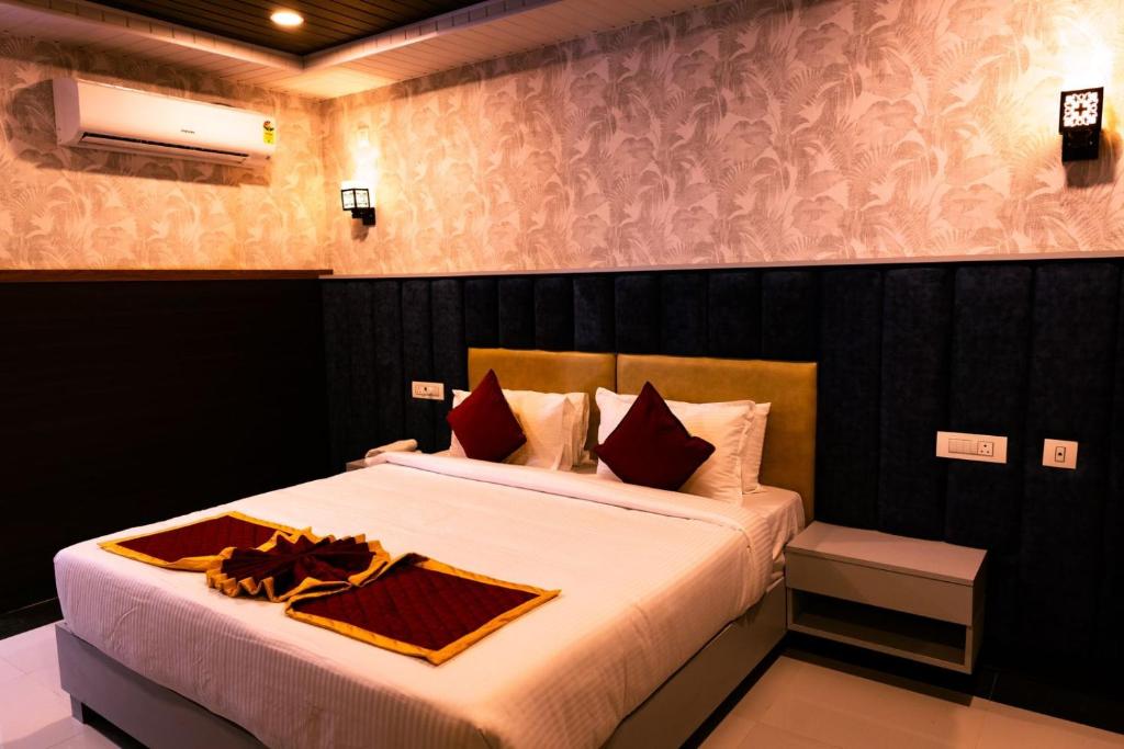 a bedroom with a bed with white sheets and red pillows at HOTEL GRAND ORCHID in Tirupati