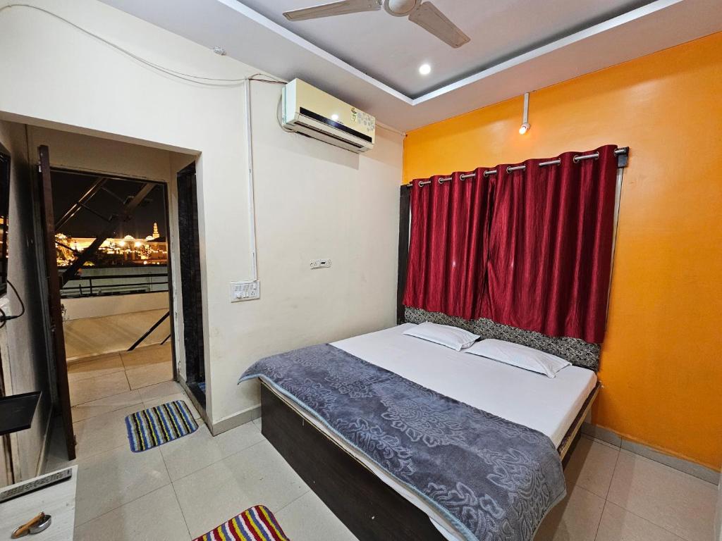 a small bedroom with a bed with a red curtain at Tiwari G Shridhara Hotel in Ujjain