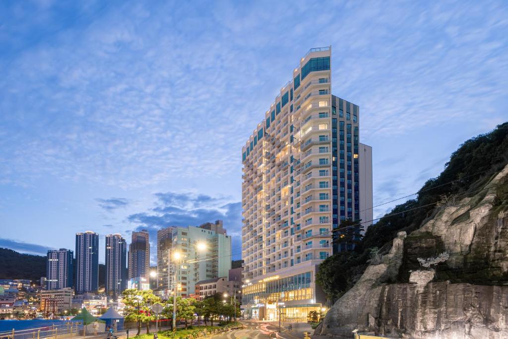 a tall building in front of a city at night at Urbanstay Busan songdo Beach in Busan