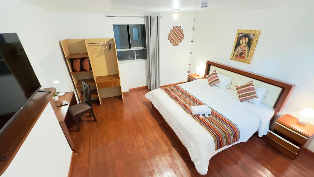 um quarto com uma grande cama branca e pisos em madeira em Casona Liberty Inn em Cusco