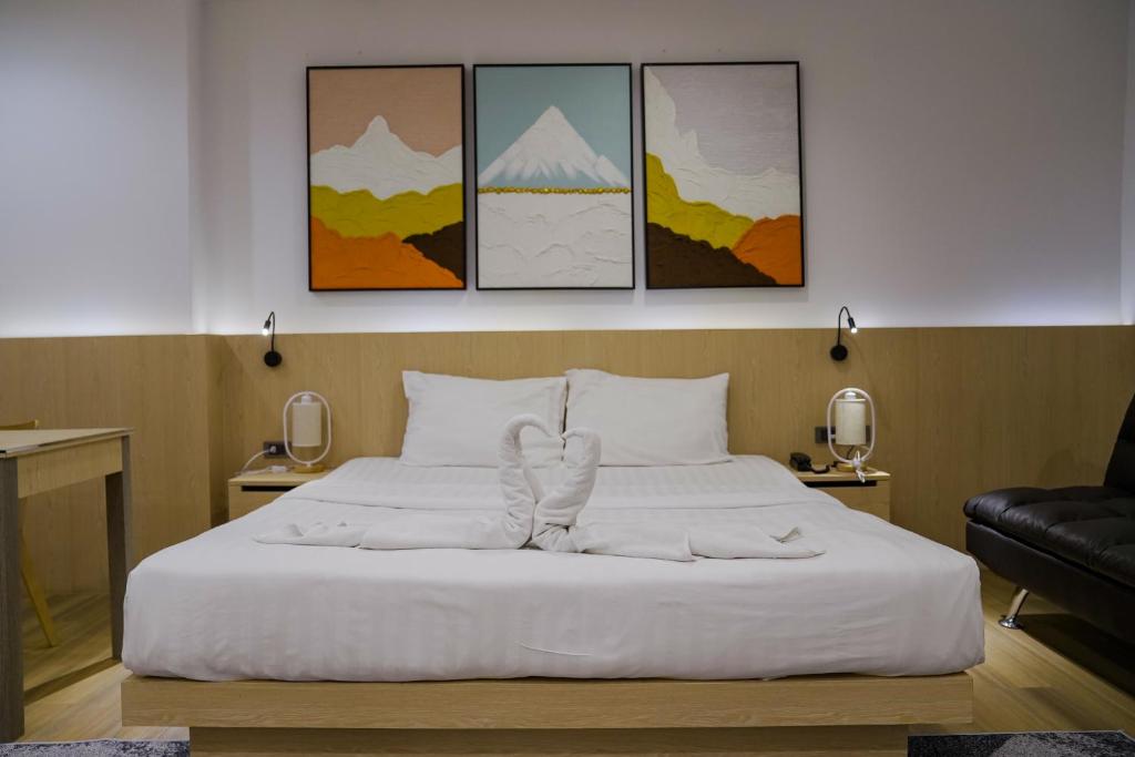 a bedroom with a white bed with four paintings at Sakura Sky Residence in Bangkok