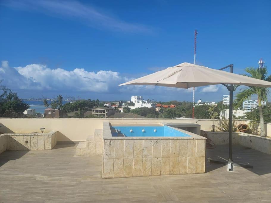 un patio con sombrilla y piscina en Ocean View Penthouse, en Boca Chica