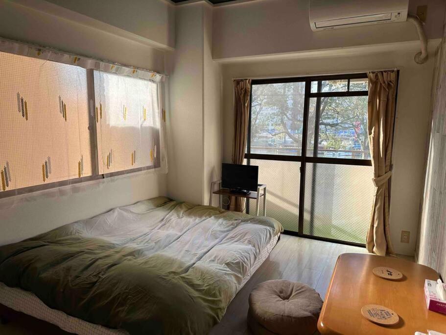 um quarto com uma cama, uma mesa e uma janela em North River 203 Blue Lotus スタジアムEdon Peace Wingの近く em Kami-nagarekawachō