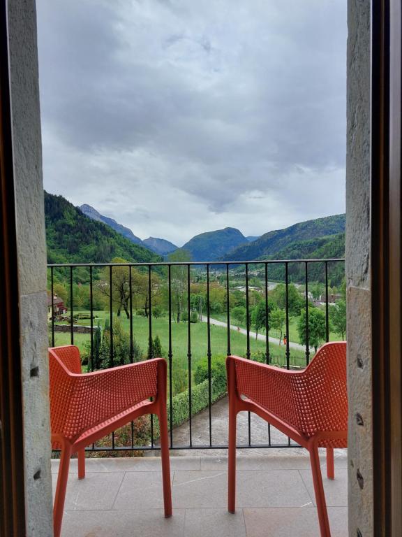 Duas cadeiras vermelhas numa varanda com vista em Residence Samont em Arta Terme