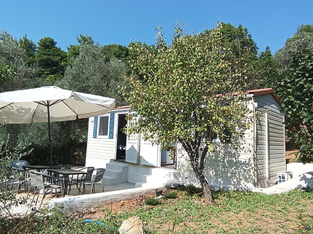 a small house with a table and an umbrella at Hillbilly cabin, 2 studios in nature with terrace and parking in Skiathos