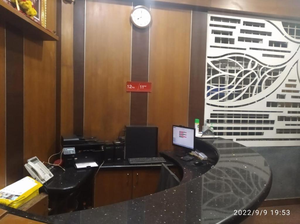 The Trinitywood Hotel & Restaurant في بانغالور: مكتب به مكتب وبه لاب توب وهاتف