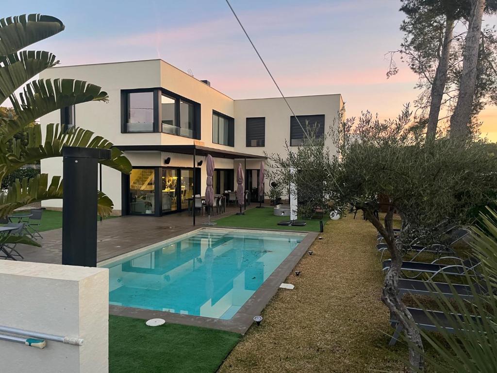 una casa con piscina frente a ella en LA CASA DE LA OLIVERA Luxurious house, en Les tres Cales