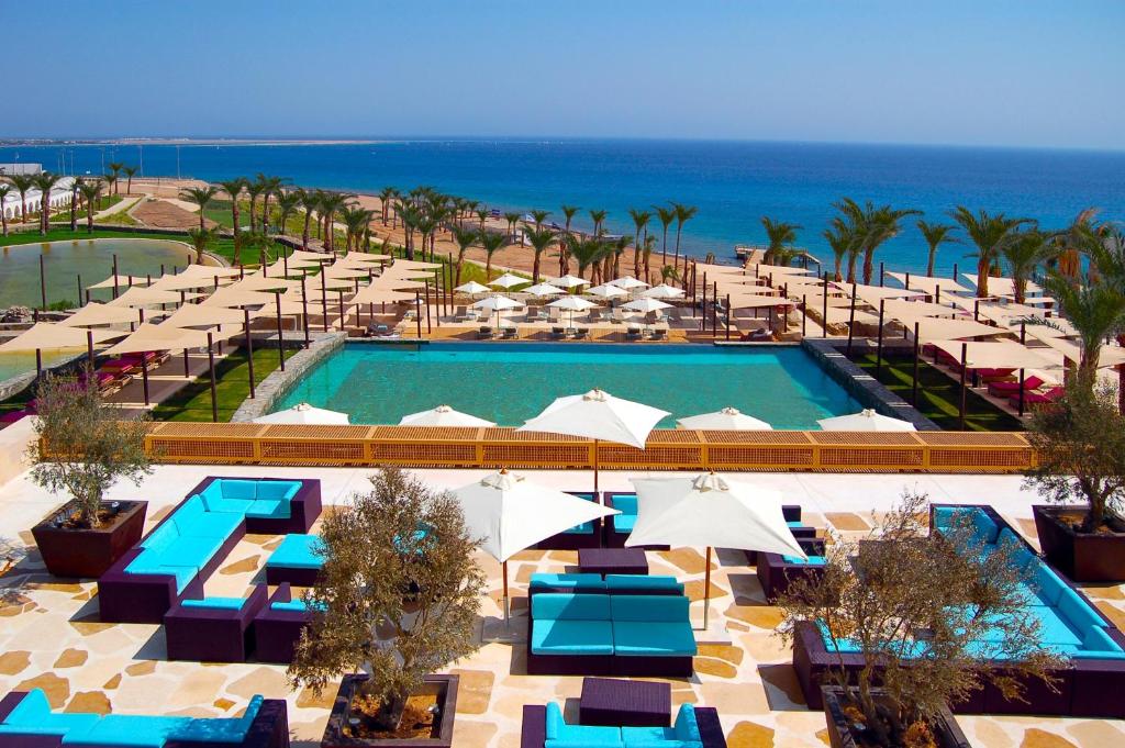 an overhead view of a pool with umbrellas and the ocean at Retac Qunay Dahab Resort & SPA in Dahab