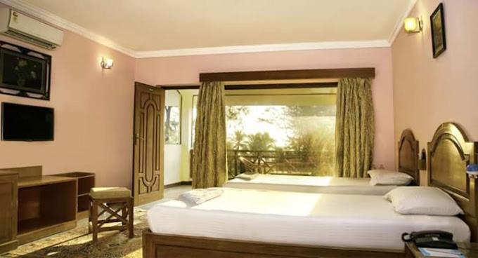a large bedroom with two beds and a window at Sea Breeze Beach Resort in Mahabalipuram