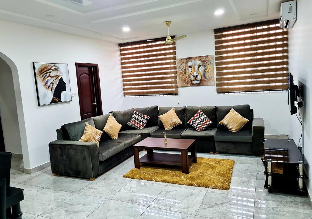 een woonkamer met een zwarte bank en een tafel bij Douglas Court Accra-Fantastic Living 1,2,3-Beds in Adenta, 5star Service, Free Wifi, 30mins to Airport, by DLA 