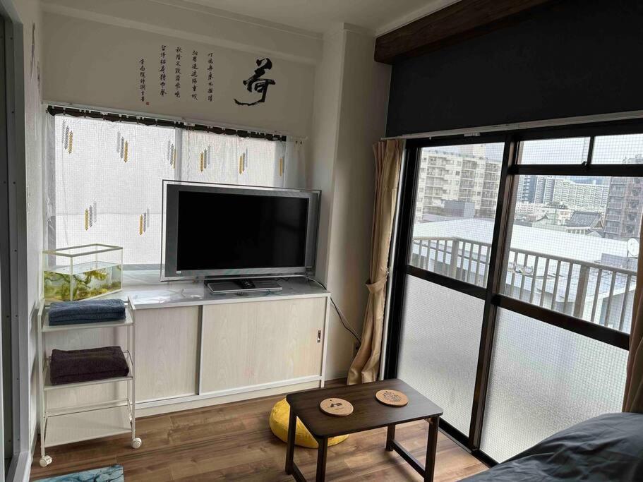 a living room with a tv and a large window at North River701 Peace Wing 7 新サッカースタジアム近辺 in Kami-nagarekawachō