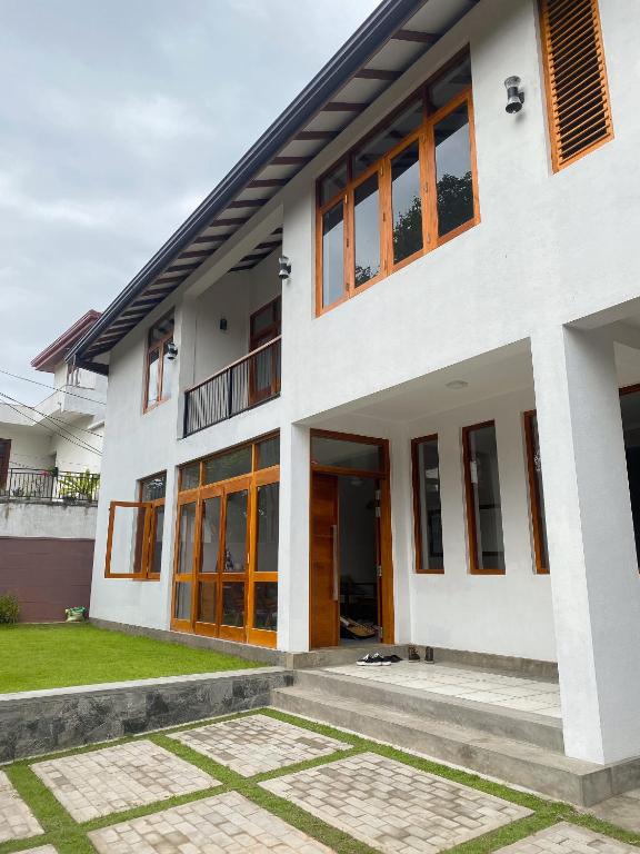 a white house with glass doors and grass at THE DOCTORS VILLA in Ragama