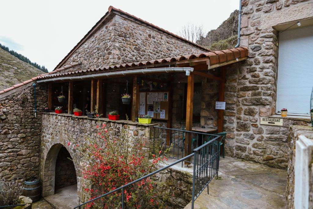 a stone building with a shop with flowers in it at AU CHAT BLEU in Saint-Laurent-les-Bains