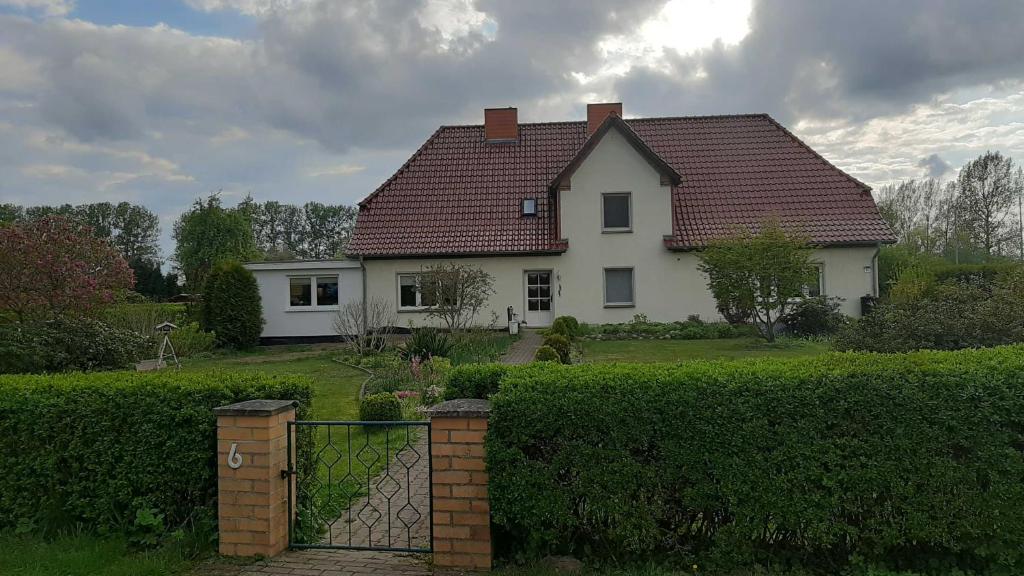 Casa blanca con techo rojo y valla en Ferienwohnung im Zanderhaus, en Sabel