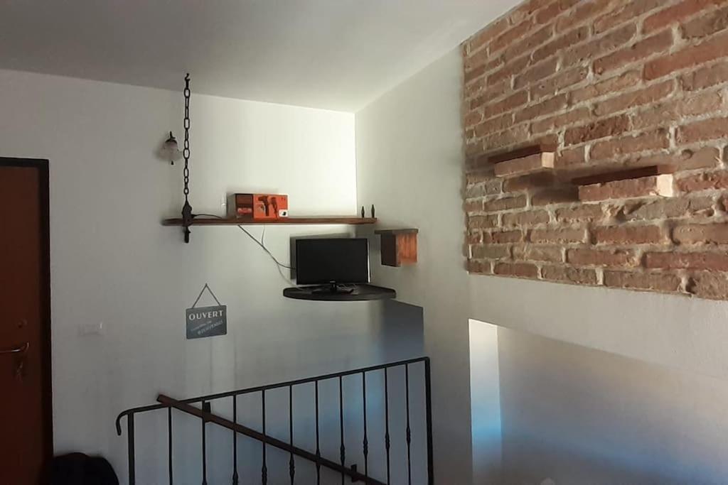 a room with a staircase with a tv and a brick wall at La Casa di Cardini in San Giacomo