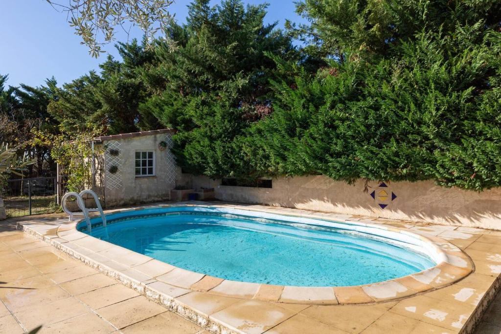 una gran piscina en un patio con árboles en Mas Provençal de 120m2 en Camargue, Avec Piscine et Parking inclus, Idéal pour des vacances, en Arles